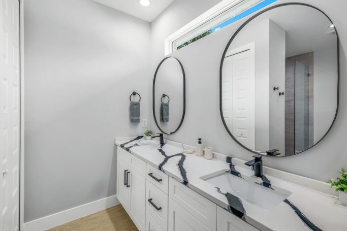 Heller, moderner Badebereich mit zwei runden Spiegeln und eleganter Waschbeckenanordnung.