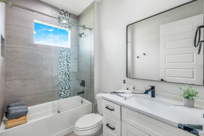 Helles Badezimmer mit Badewanne, Dusche, Waschbecken und modernen Oberflächen.